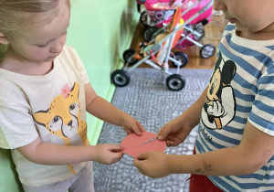 Dzieci na dywanie łączą rozcięte koła w całość, które są w tych samych kolorach