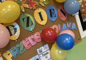 Na tablicy wiszą dekoracje z okazji Dnia Przedszkolaka oraz kolorowe balony