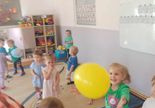 Dzieci tańczą i bawią się żółtym balonem.