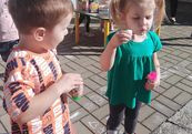 Dziewczynka i chłopiec puszczają bańki mydlane.
