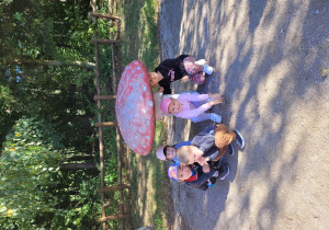 Dzieci pozują do zdjęcia przy figurce muchomora.