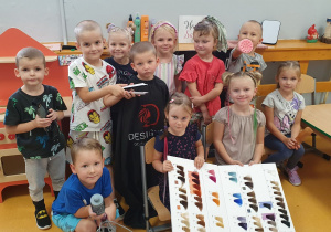 Dzieci z grupy Liski pozują do wspólnego zdjęcia, prezentując akcesoria fryzjerskie.