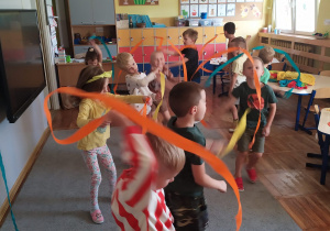 Dzieci tańczą i wirują bibułkami w kolorach jesiennych.