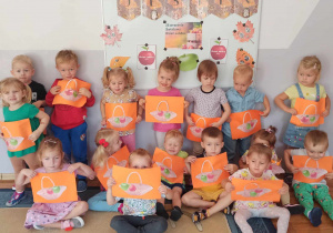 Dzieciaki z grupy Biedronki pozują do zdjęcia z własnoręcznie wykonaną pracą plastyczną – koszyczki z jabłuszkami.