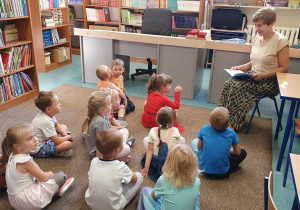 Dzieci słuchają bajki czytanej przez Panią bibliotekarkę.