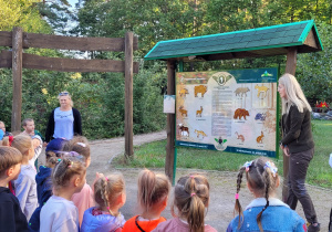 Dzieci oglądają tablicę ze zwierzętami leśnymi i słuchają odgłosów tych zwierząt