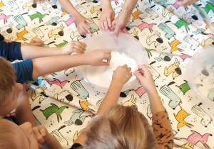 Dzieci wyrabiają masę z mąki ziemniaczanej potrzebną do kolejnego eksperymentu.