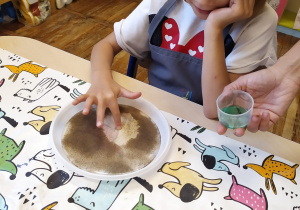 Dziewczynka robi eksperyment z pieprzem i płynem do mycia naczyń.