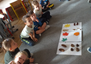 Dzieci oglądają liście i owoce różnych drzew.