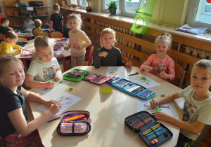 Dzieci kolorują obrazek drzewa.