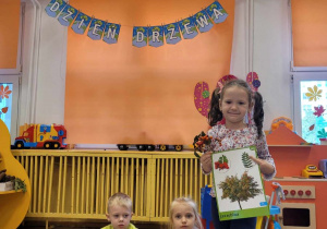 Dziewczynka prezentuje drzewo jarzębinę oraz jej dar jesieni.