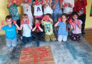 Dzieci z grupy Słoneczka odbijały pomalowane ręce na kartonie tworząc liście.