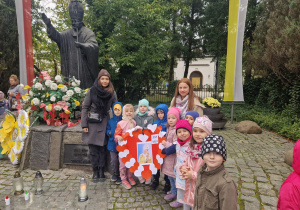 "Odkrywcy" pozują do zdjęcia z nauczycielkami pod pomnikiem Jana Pawła II.